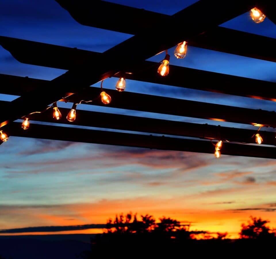 Outdoor lighting on a pergola at sunset.